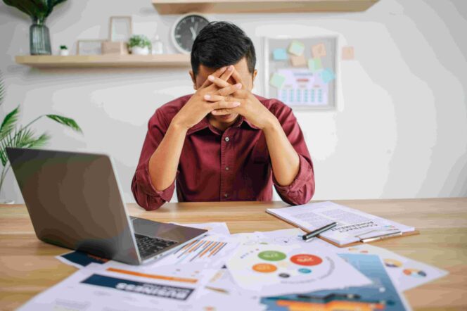 
					Man working with laptop and paperwork with stress
